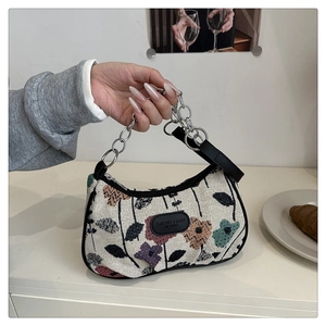 Close-up of floral woven fabric bag with metal chain strap and fashion logo patch