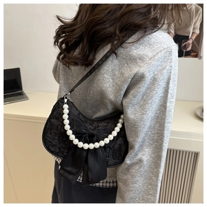 Detail of black jacquard crescent bag with bow accent and large pearl shoulder chain