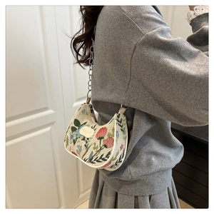 Detailed embroidery of floral and strawberry patterns on a chic jacquard hobo bag with chain
