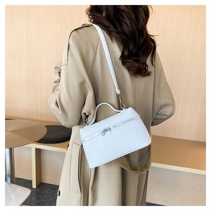 Close-up of white lychee pattern crossbody bag worn with a khaki trench coat