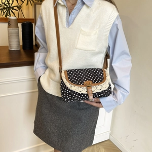 Sac bandoulière vintage en toile à pois avec bordure en dentelle porté par un modèle