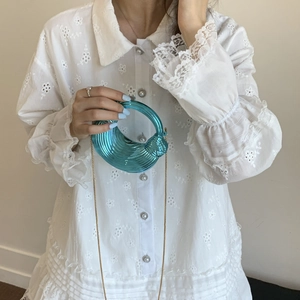 Metallic blue pleated ring handbag with gold chain strap held by a female model