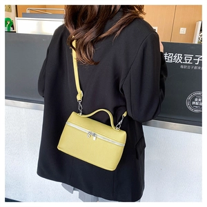 Litchi pattern yellow crossbody box bag with silver zippers shown in a cafe setting