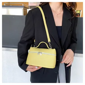 Detail of yellow litchi grain leather texture on a compact boxy crossbody handbag