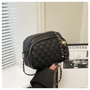 Macro detail of quilted black leather camera bag with golden chain and ball charm