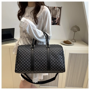 Detail of printed travel bag with leather straps and gold-tone metal hardware accessories