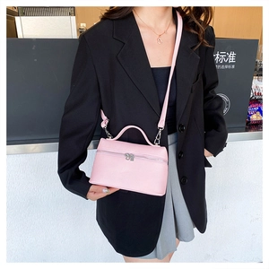 Detailed view of pink lychee leather crossbody bag worn with a black blazer for office style