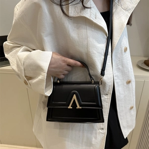 Minimalist black leather crossbody bag with gold hardware shown on a model