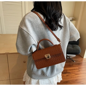 Brown crocodile pattern crossbody bag featuring a golden twist-lock and top handle