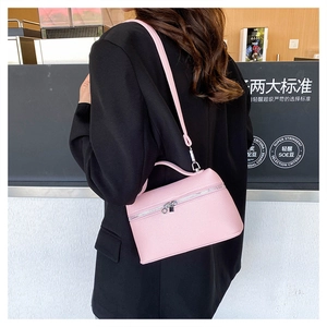 Pink lychee texture vanity bag with top handle and crossbody strap on model's shoulder