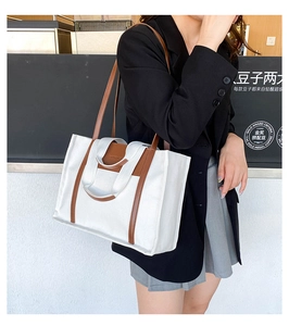 Detail of canvas tote bag showing brown leather handles and adjustable shoulder straps
