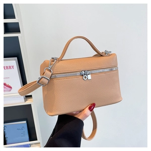 Detail of lychee textured leather crossbody bag with silver circular zipper hardware