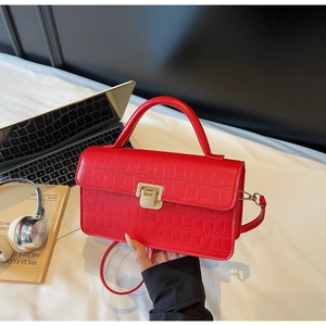 Close-up of red crocodile embossed handbag with golden metal lock and top handle