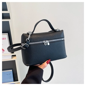 Detail of black lychee grain leather crossbody bag with silver zippers and top handle