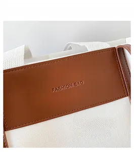 Close-up of canvas tote bag with brown leather strap and Fashion Bag embossed logo