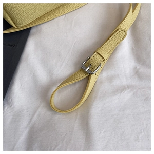 Close-up of adjustable silver buckle and yellow litchi grain leather strap on a bucket bag