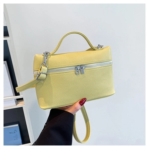 Detail of light yellow lychee pattern leather bag with silver zippers and top handle