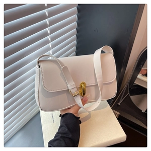 Detail of minimalist cream leather shoulder bag with gold twist lock and adjustable strap