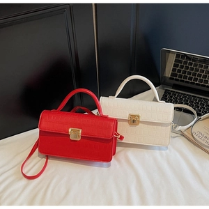 Detail of red and white crocodile texture handbags with elegant gold twist lock closure