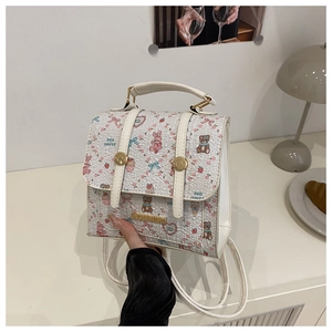 Close-up of strawberry and bear print pattern on mini white faux leather backpack