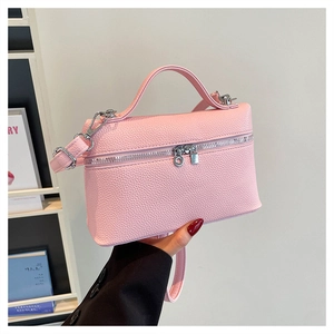 Detail of pink lychee leather crossbody bag with dual silver zippers and top handle