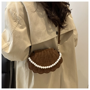 Detail of vintage brown suede shell bag featuring white pearl chain strap on model