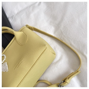 Close-up of yellow leather bucket bag with pearl and lace pendant details