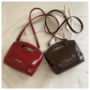 Detail of burgundy and brown patent leather tote bags with hollow handles and strap