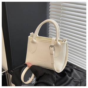 Detail of white lychee leather bucket bag with circular handle and metal buckle