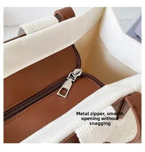Close-up of smooth metal zipper detail on canvas tote bag with brown leather trim