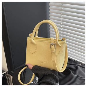 Detail of yellow lychee pattern faux leather handbag with shoulder strap and text