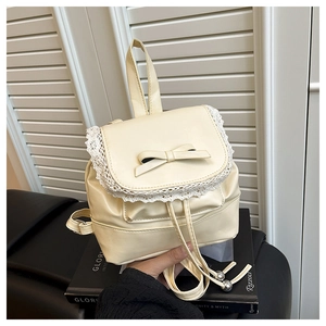 Detailed shot of cream-white leather mini backpack with lace trim and bow accent