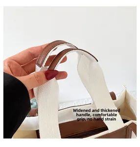 Detail of reinforced wide canvas strap with ergonomic brown leather grip on tote bag