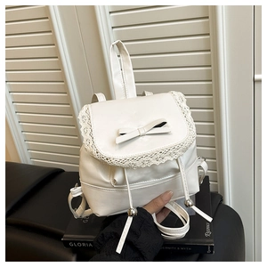 Detail of white PU leather backpack featuring delicate lace trim and ribbon bow decoration