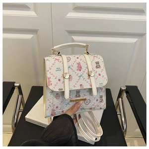 Close-up of a white faux leather bag with cute cartoon prints and gold metal hardware