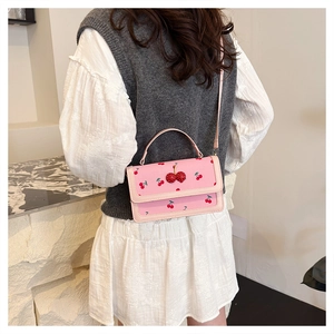 Detailed view of a pink crossbody bag with cherry patterns and 3D cherry accents