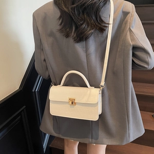 White crocodile pattern crossbody bag with gold buckle shown on a stylish model