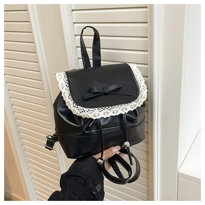 Close-up of black leather mini backpack featuring white lace trim and bow knot detail