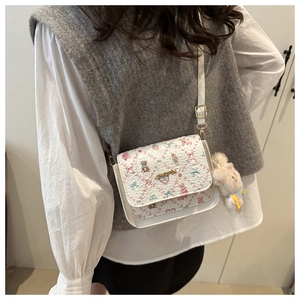 Close-up of white crossbody bag with cartoon bear prints and cute plush bunny charm