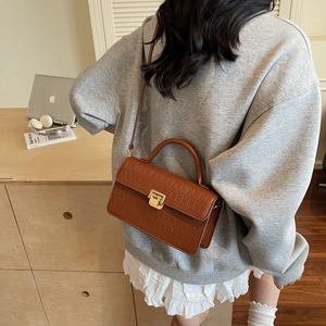 Brown crocodile embossed tote bag with gold buckle shown in a lifestyle setting