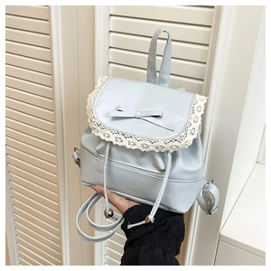 Detail of light blue mini backpack with lace trim, bow, and metallic drawstring balls