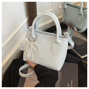 Detail of light blue lychee texture handbag with pearl lace bow and metal ring buckle