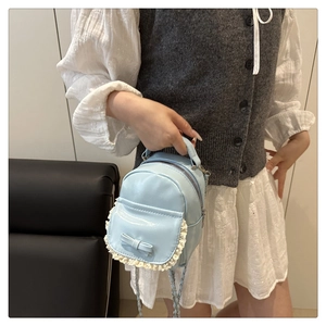 Close-up of light blue mini backpack with lace trim and bow on a model outfit