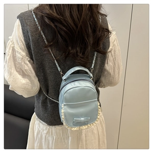 Detail of light blue bow backpack with white lace trim and metal chain strap decoration