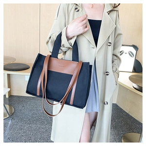 Detail of canvas tote bag with brown leather trim and dual handles for daily use