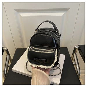 Close-up of black leather backpack featuring white lace trim and bow knot detail