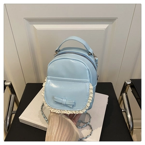 Detail of light blue patent leather mini backpack with lace trim and bow accent