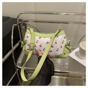 Detail of cherry print baguette bag with green trim and decorative drawstrings