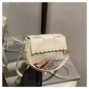 Détail du sac à main tressé crème avec bords festonnés et bandoulière chaîne dorée