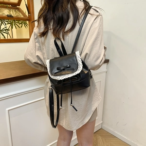 Mini black leather backpack with white lace trim and bow knot on model back